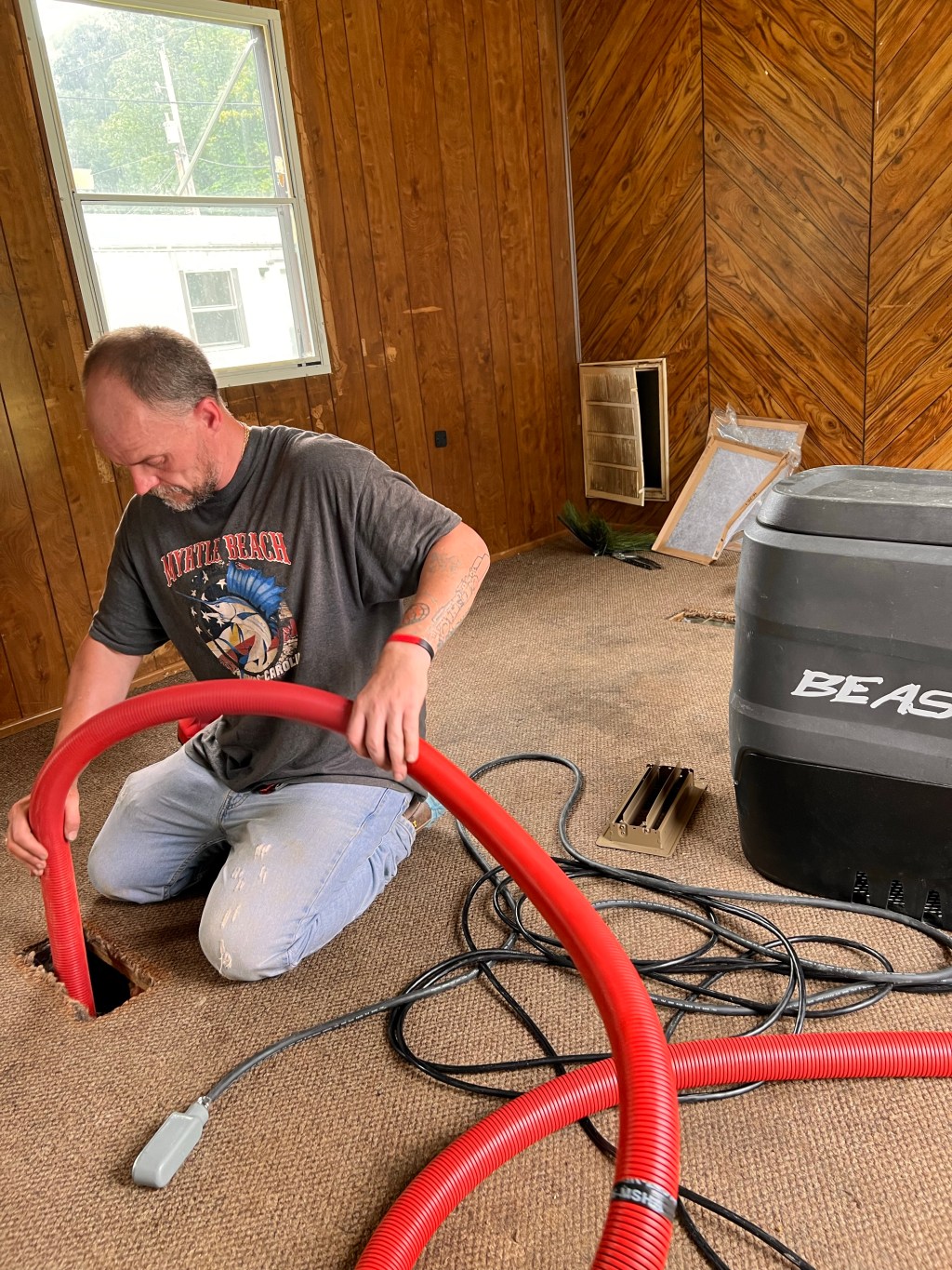 a man kneeling down on the floor with a hose